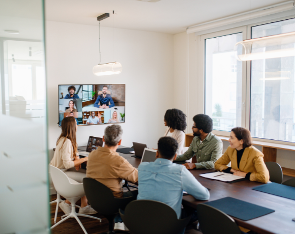 Medewerkers in een moderne hybride vergaderruimte die met één druk op de knop een meeting starten via Unite.